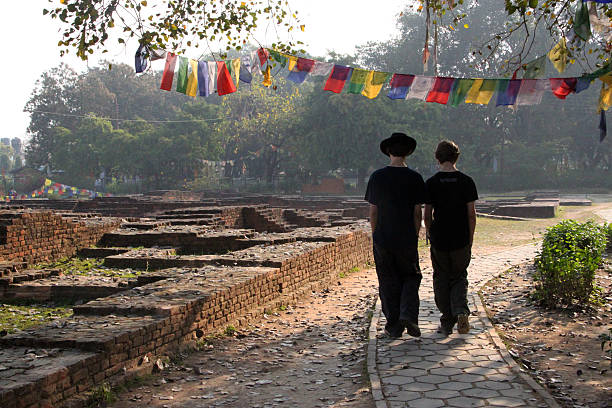 Two people walking through ruins with prayer flags.