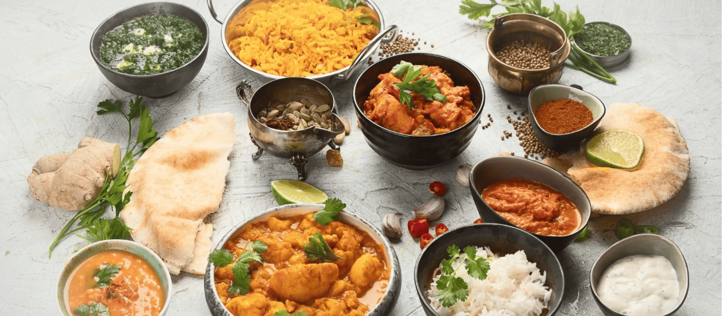 Flat lay of authentic Himachali and Tibetan cuisine featuring traditional curries, steamed breads, and spices popular in Dharamshala