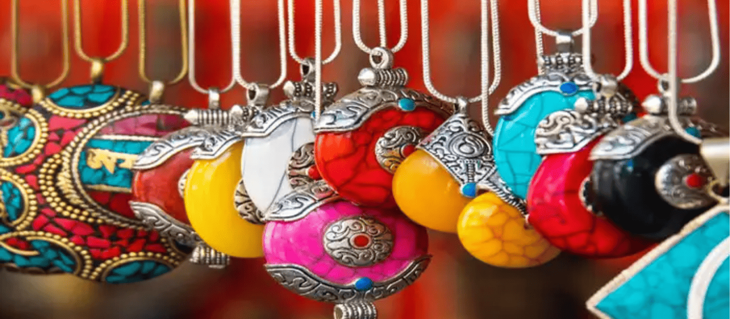 Close-up of vibrant handmade Tibetan-style necklaces and pendants featuring intricate silverwork and colorful stones like turquoise and coral, representing the traditional handicrafts available in Kalimpong