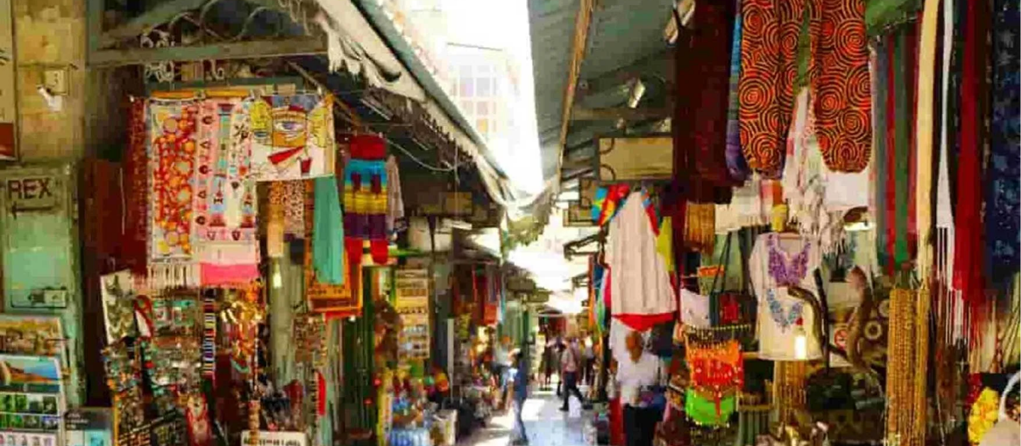 Vibrant narrow street market in Ziro Valley, Arunachal Pradesh, featuring shops filled with colorful traditional Apatani textiles, woven shawls, and local handicrafts