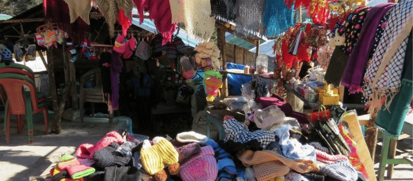 Roadside souvenir stall in North Sikkim displaying colorful hand-knitted woolen hats, scarves, and gloves, commonly found near Yumthang Valley and Lachung