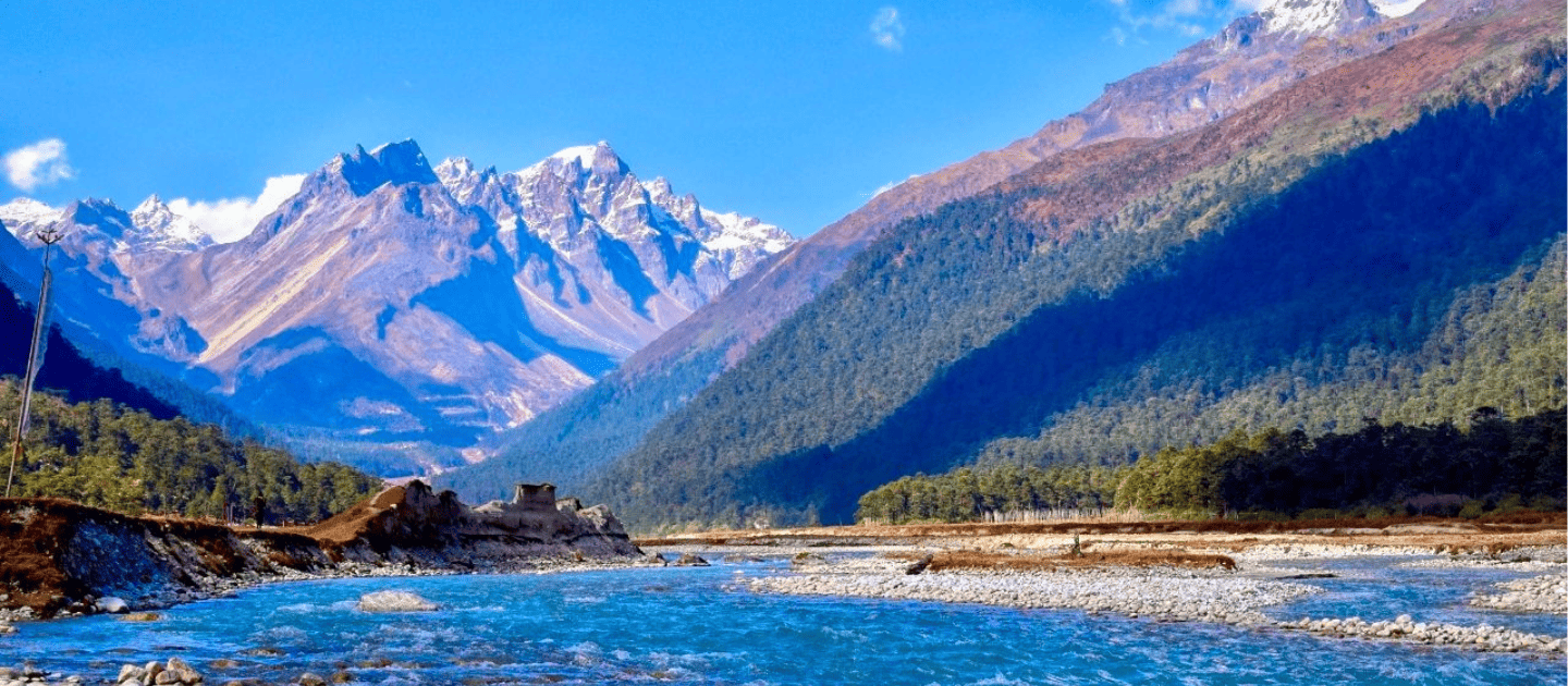 Breathtaking view of Harsil Valley near Uttarkashi, featuring the crystal-clear Bhagirathi River flowing amidst lush pine forests and snow-capped Himalayan peaks