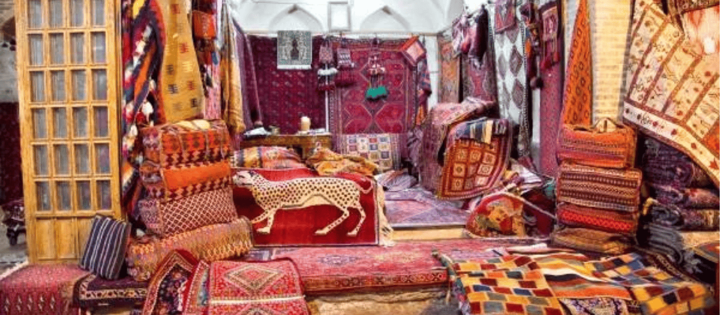 Interior view of a traditional Kashmiri handicraft shop displaying vibrant hand-knotted carpets, intricate rugs, and embroidered cushions