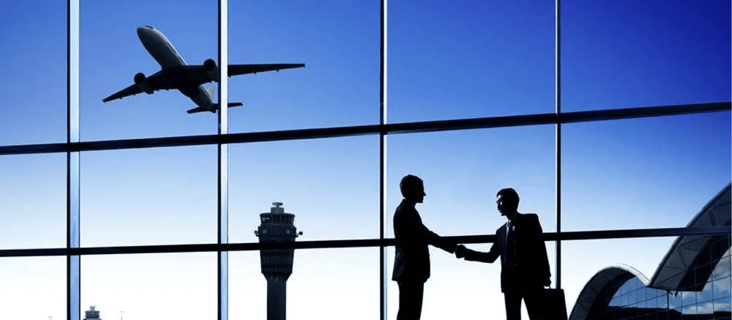 Silhouette of two business professionals shaking hands at an airport terminal with an airplane taking off in the background