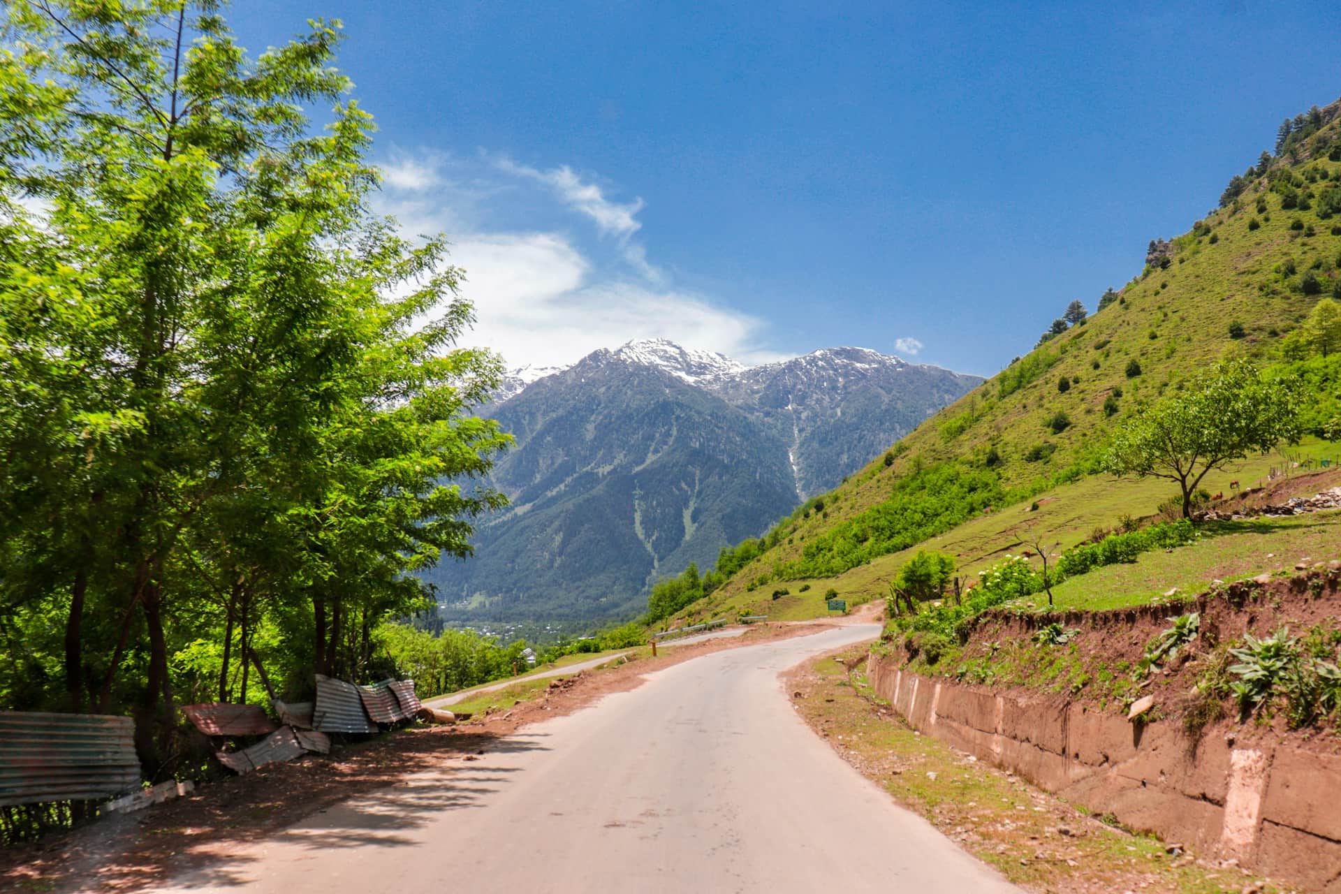 Scenic mountain road in Kashmir valley with green hills and snow peaks Scenic mountain road in Kashmir valley with green hills and snow peaks